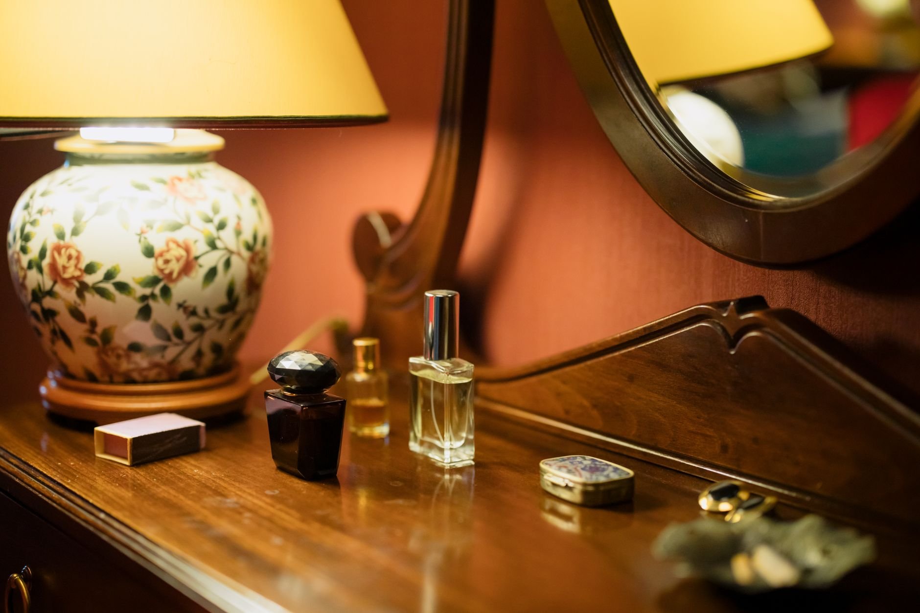A stylish perfume and decor arrangement on a wooden table with warm lighting.